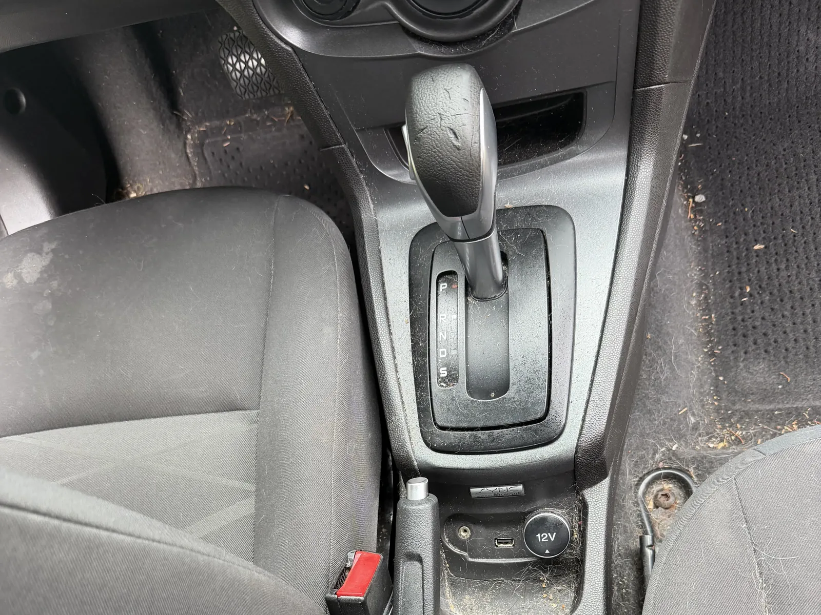 Ford center console before interior detailing, with debris around the controls and cup holders.
