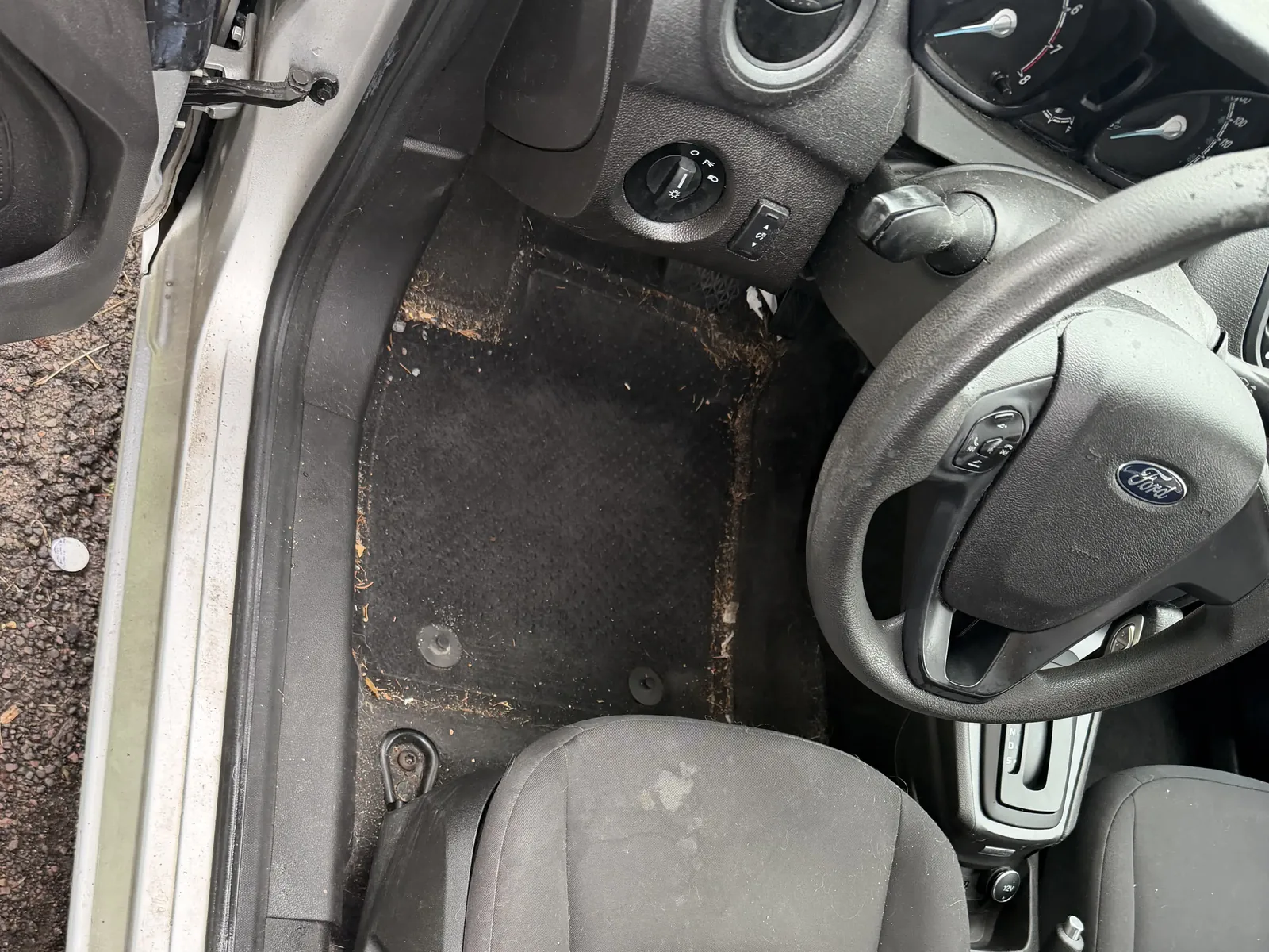 Ford driver area before interior detailing, with debris visible on the floor.